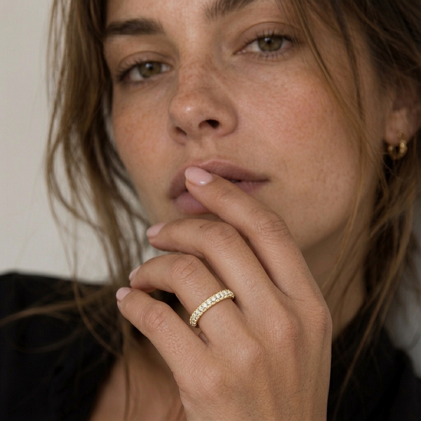 Close-up of a woman with a gold ring on her finger, wearing a black top.