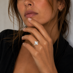 Close-up of a woman's hand wearing a diamond ring with a neutral background