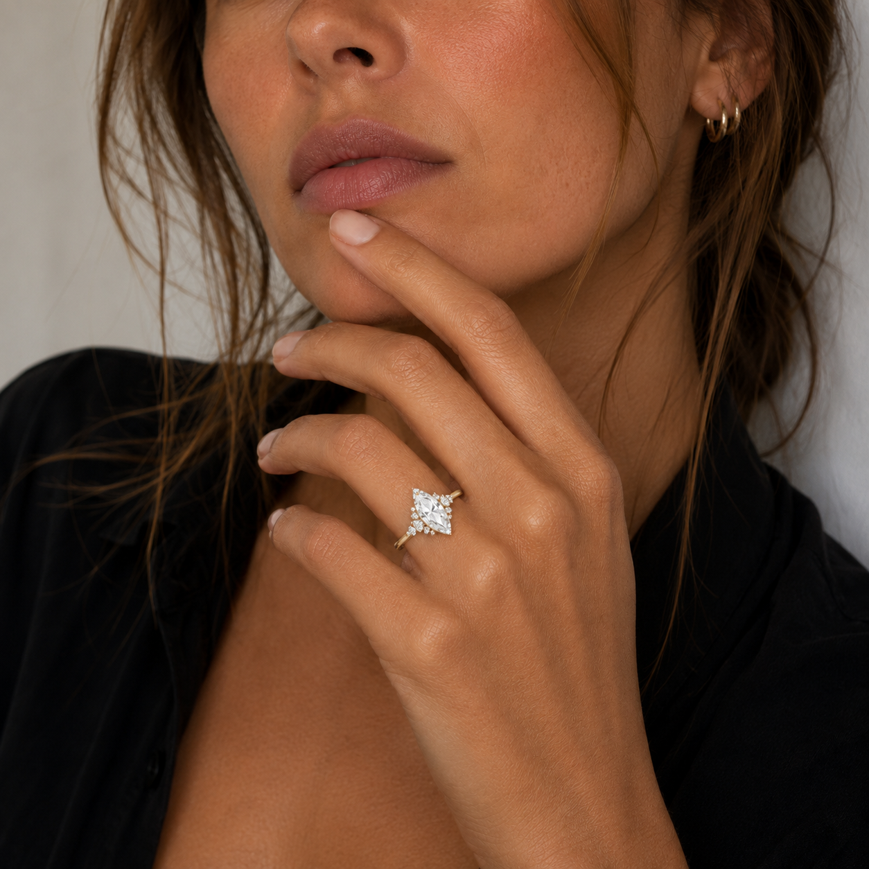 Close-up of a woman's hand wearing a diamond ring with a neutral background