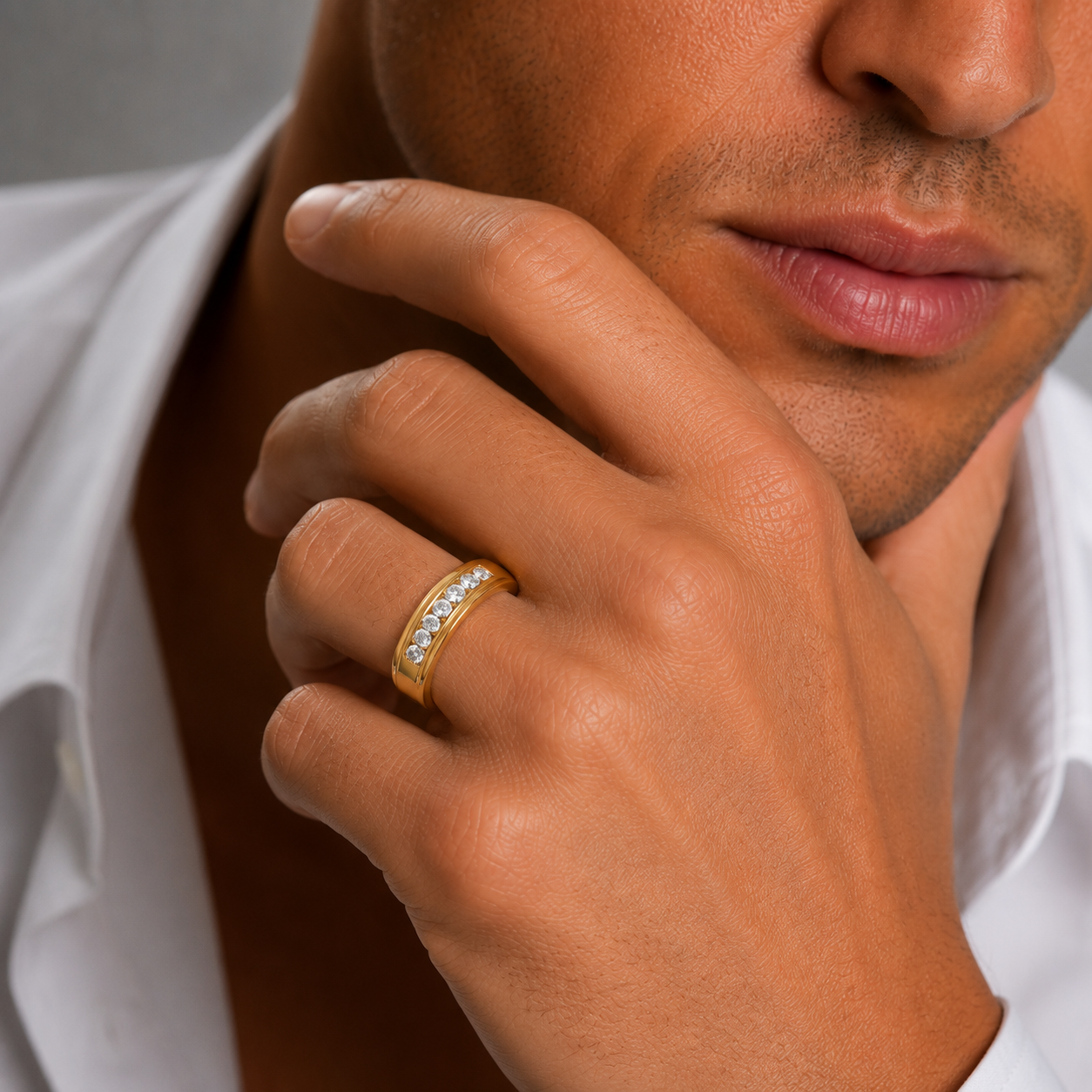 Close-up of a hand wearing a gold ring with a white shirt background
