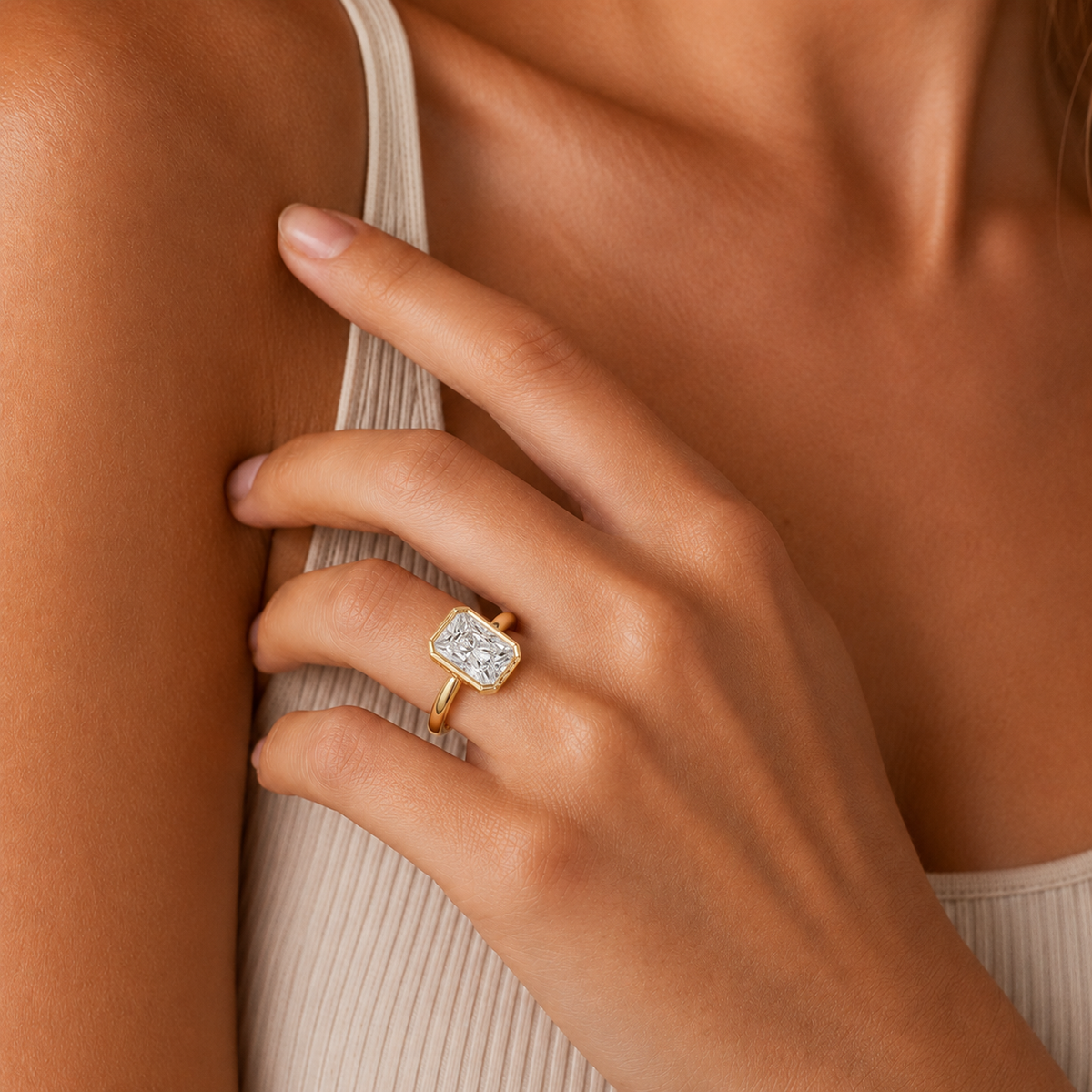 Close-up of a hand wearing a gold ring with a diamond on a neutral background