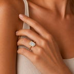 Close-up of a hand wearing a gold ring with a diamond on a neutral background