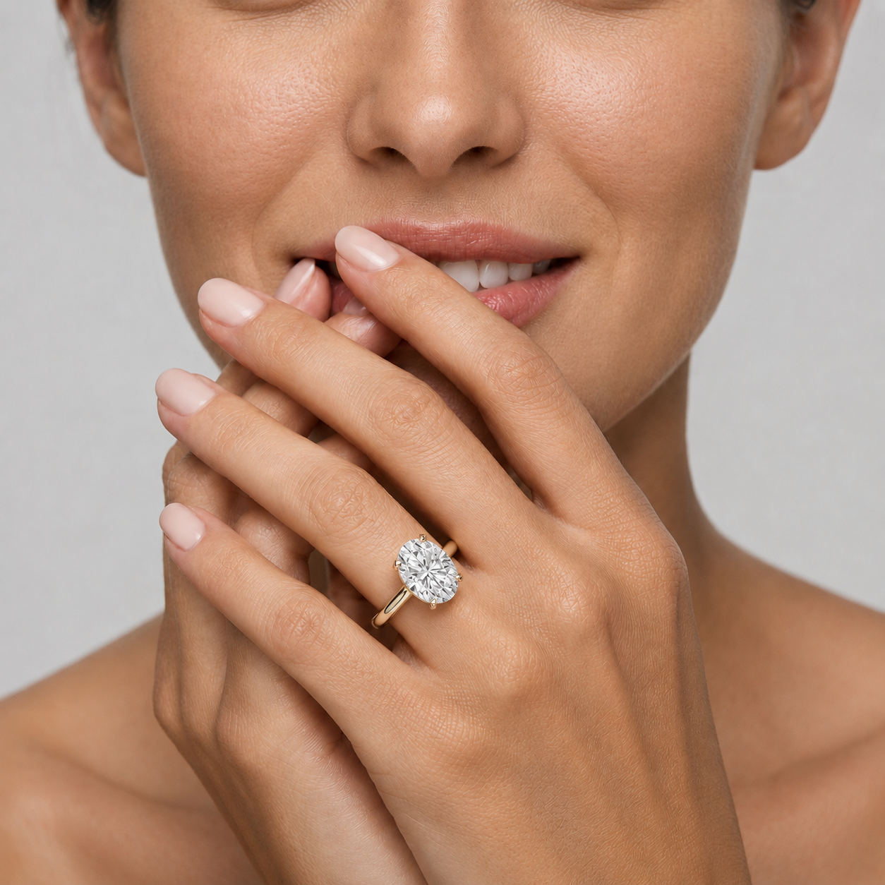 Close-up of a hand wearing a diamond ring with a neutral background