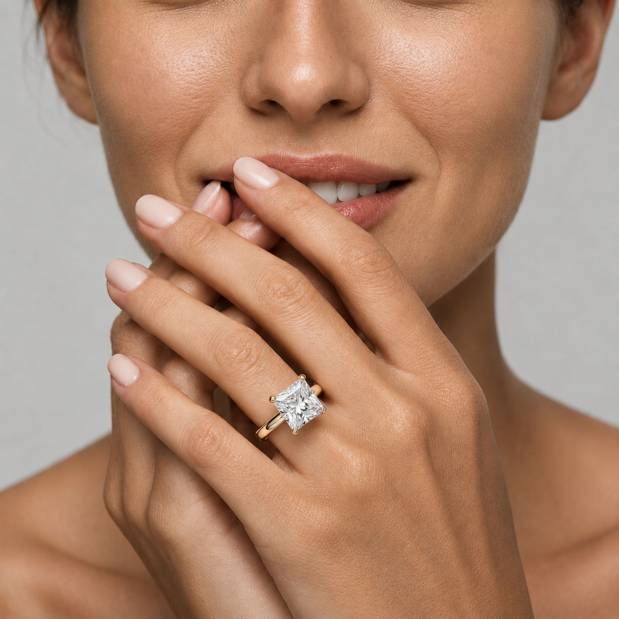 Close-up of a hand wearing a diamond ring with a neutral background