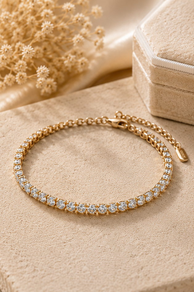 Gold necklace and bracelet on a soft beige fabric background with dried flowers.