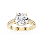 A yellow gold engagement ring featuring a large round-cut diamond center stone and smaller diamonds set along the shoulders, shown on a clean white background.