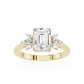 A yellow gold engagement ring featuring a large emerald-cut center diamond flanked by smaller marquise-cut side diamonds, set on a polished band against a white background.