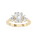 A yellow gold engagement ring featuring a large emerald-cut center diamond flanked by smaller marquise-cut side diamonds, set on a polished band against a white background.